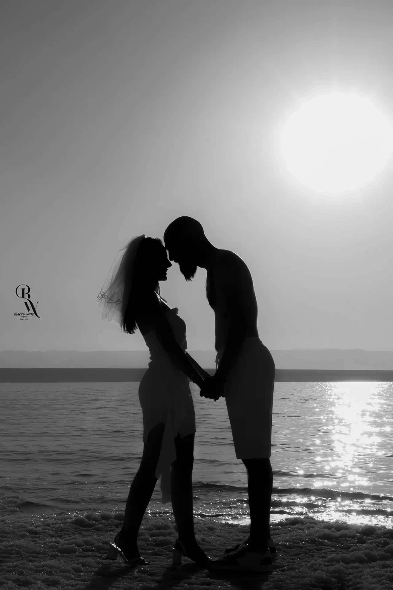 A couple in silhouette against the sun over the water
