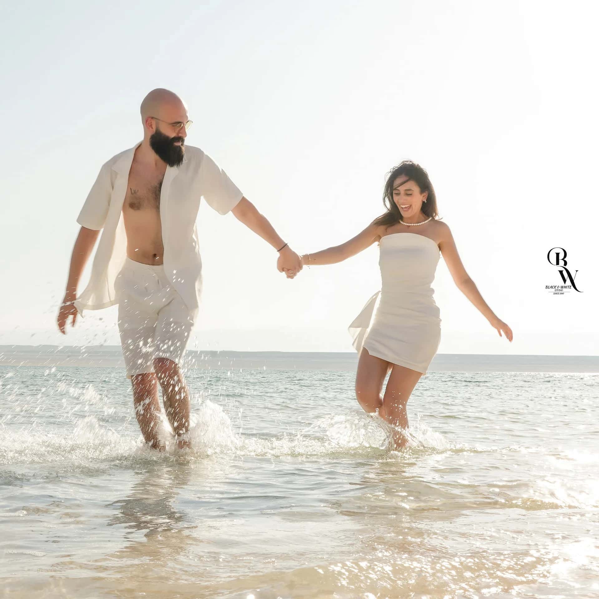 A couple running hand in hand through the water