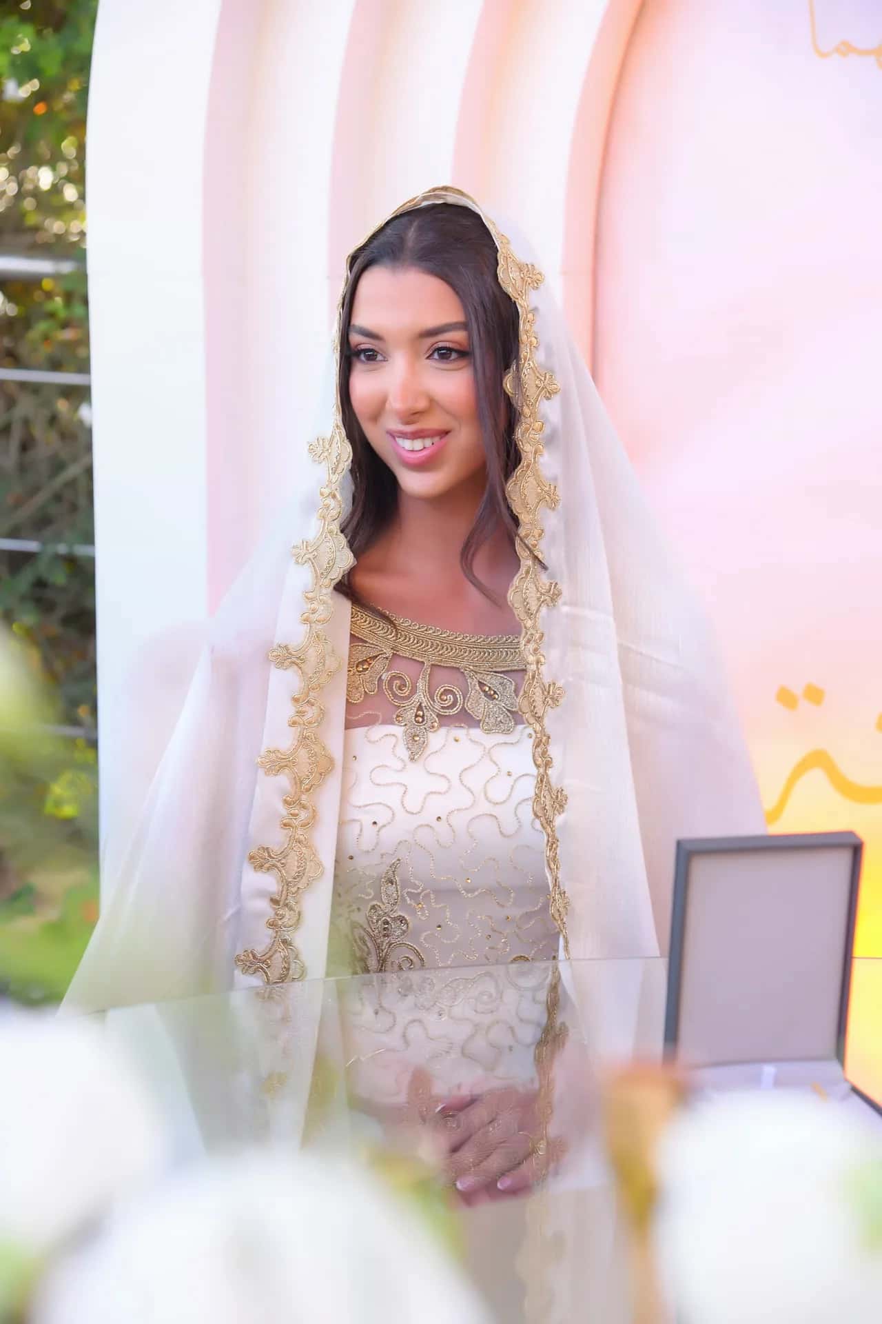 A bride in a lace veil on the day of her katb kitab