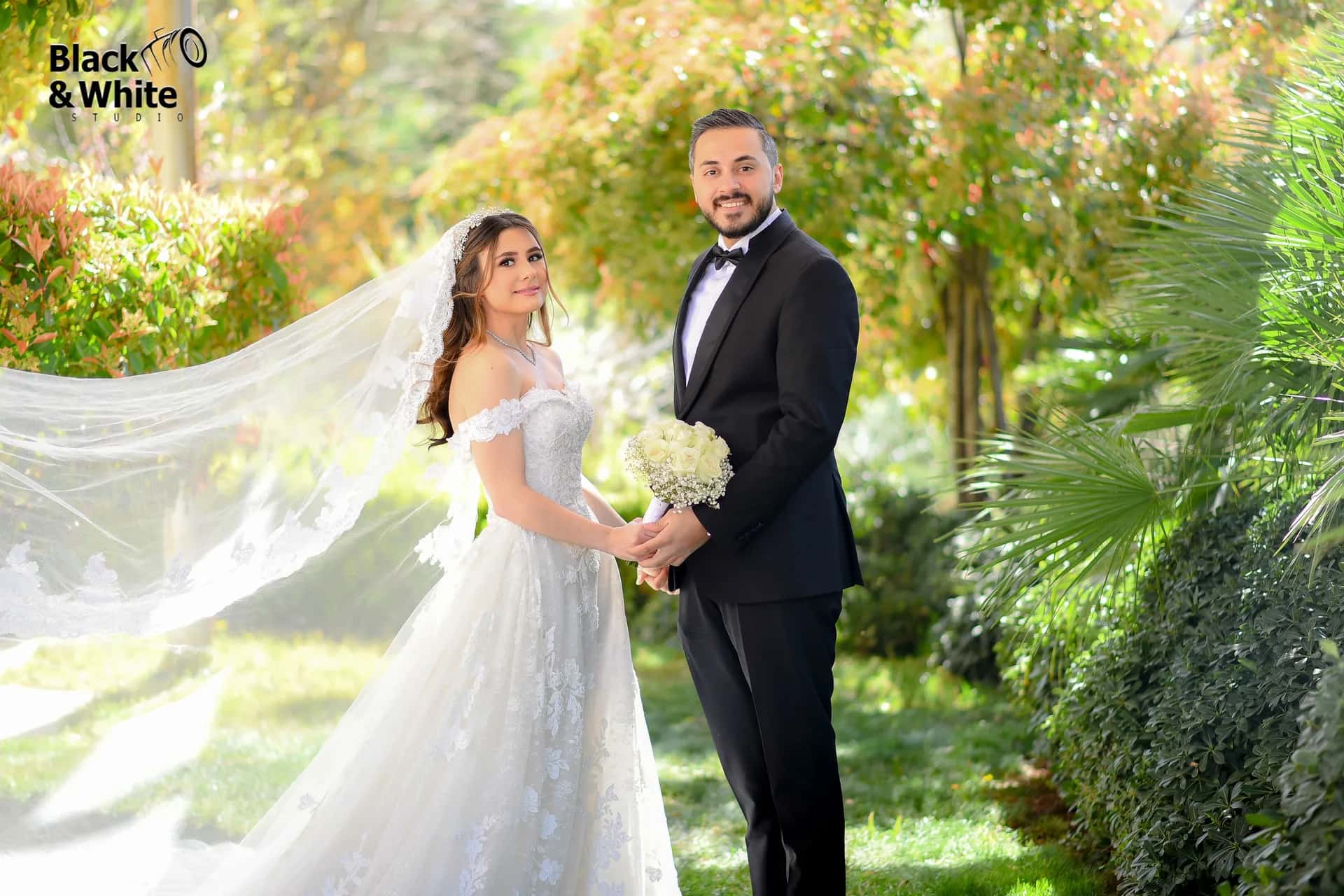 A couple under a long veil in a green garden