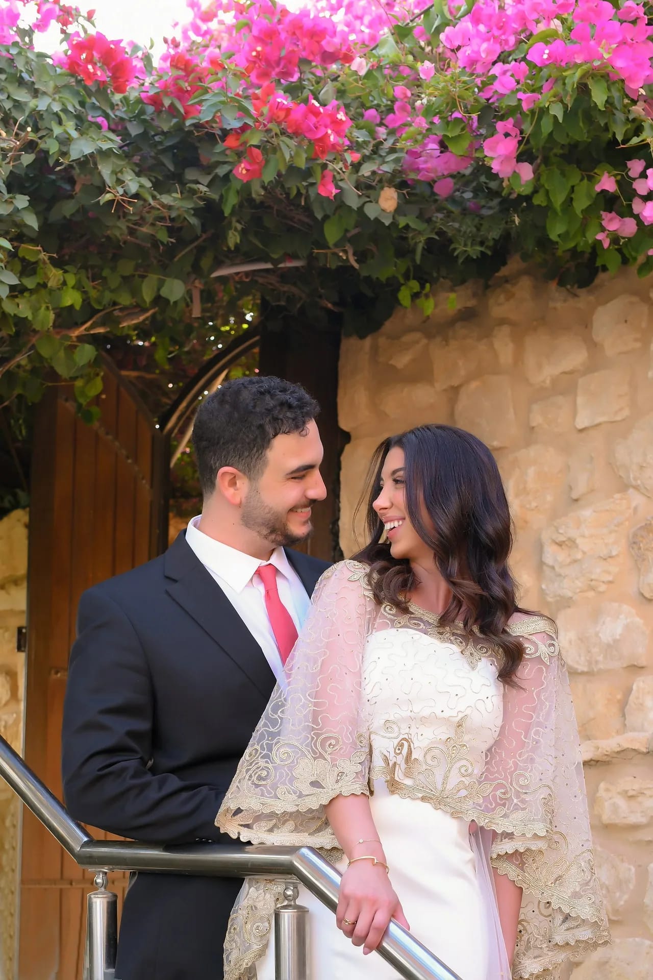 A couple on stone steps under bougainvillea