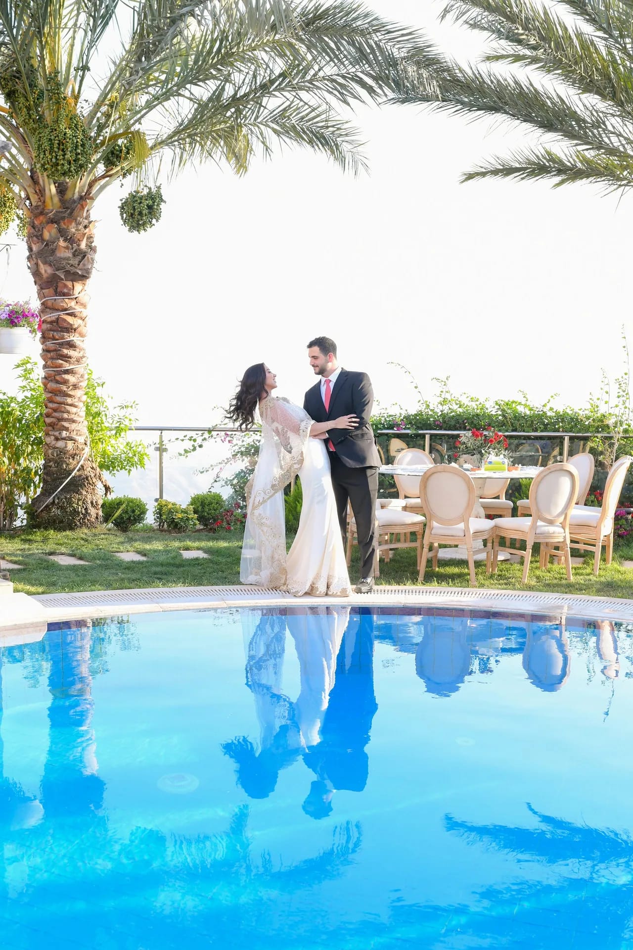 A couple beside a swimming pool among palm trees