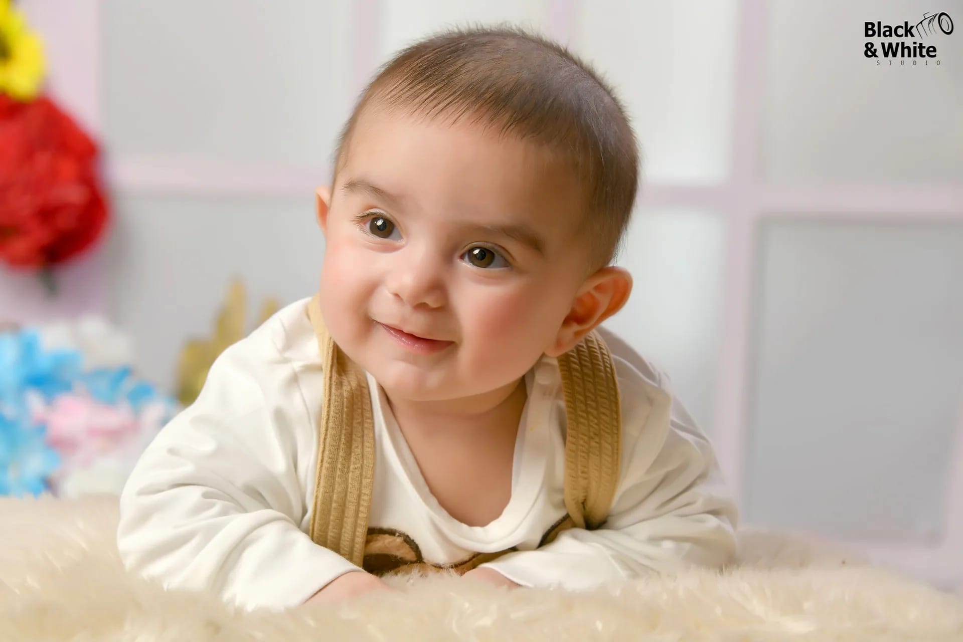A baby smiling on a soft blanket in the studio