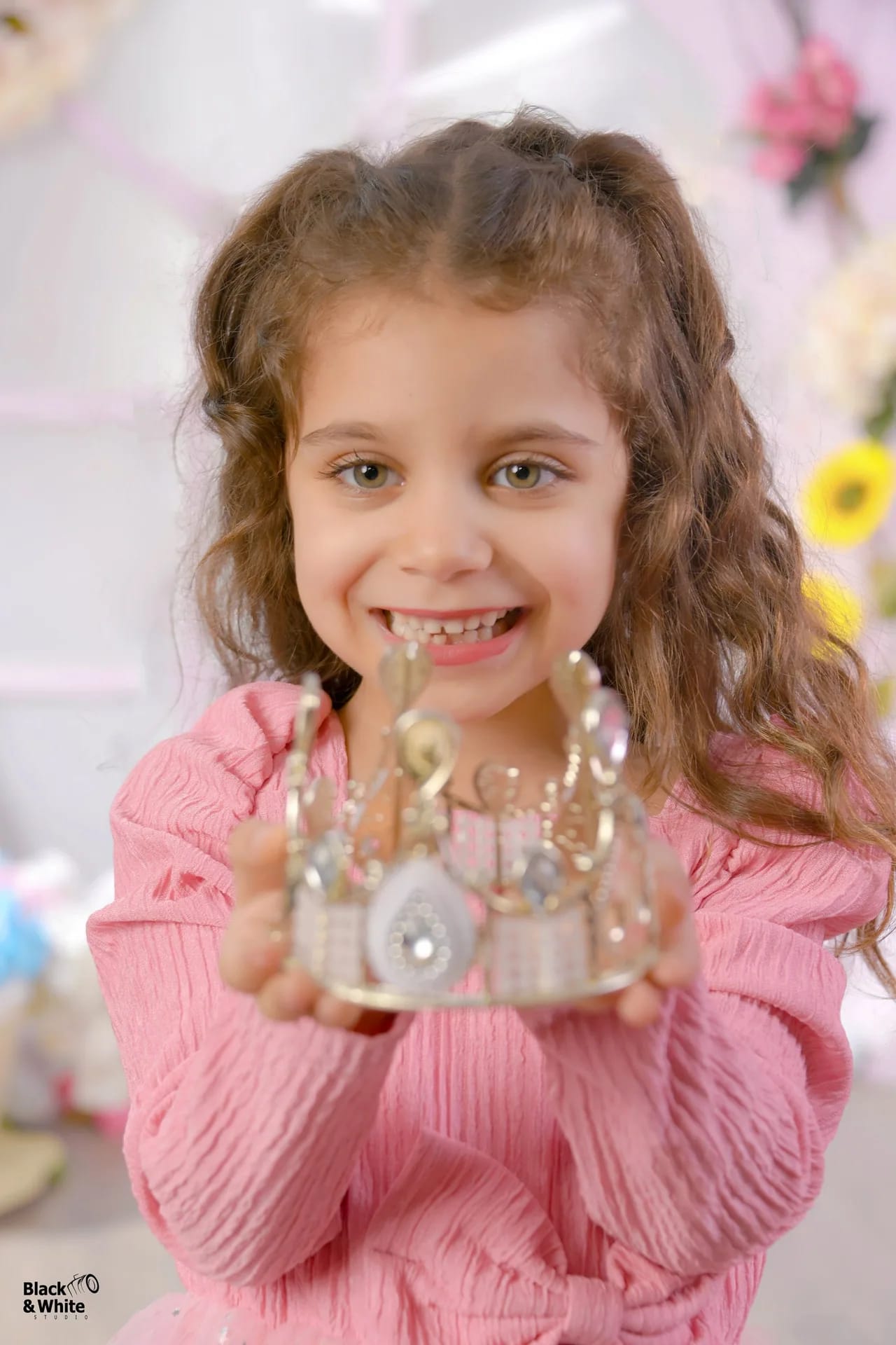 A girl holding a small crown and smiling