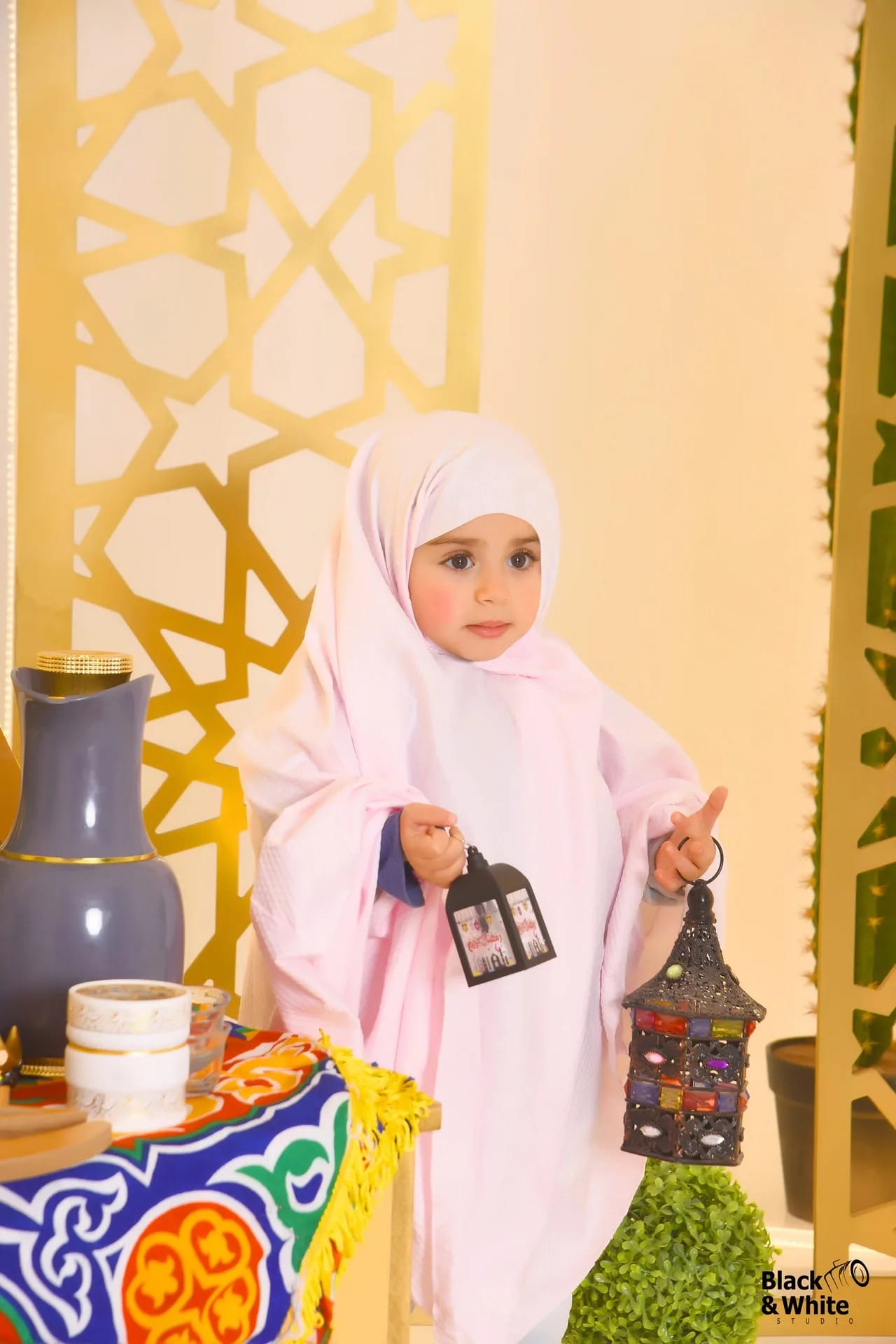 A small girl in white holding a lantern in the Ramadan set