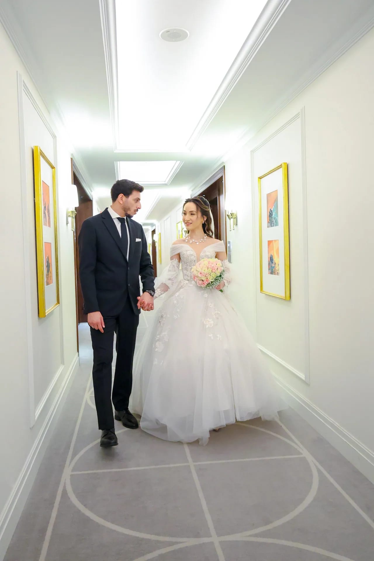 A couple framed at the end of a long white corridor