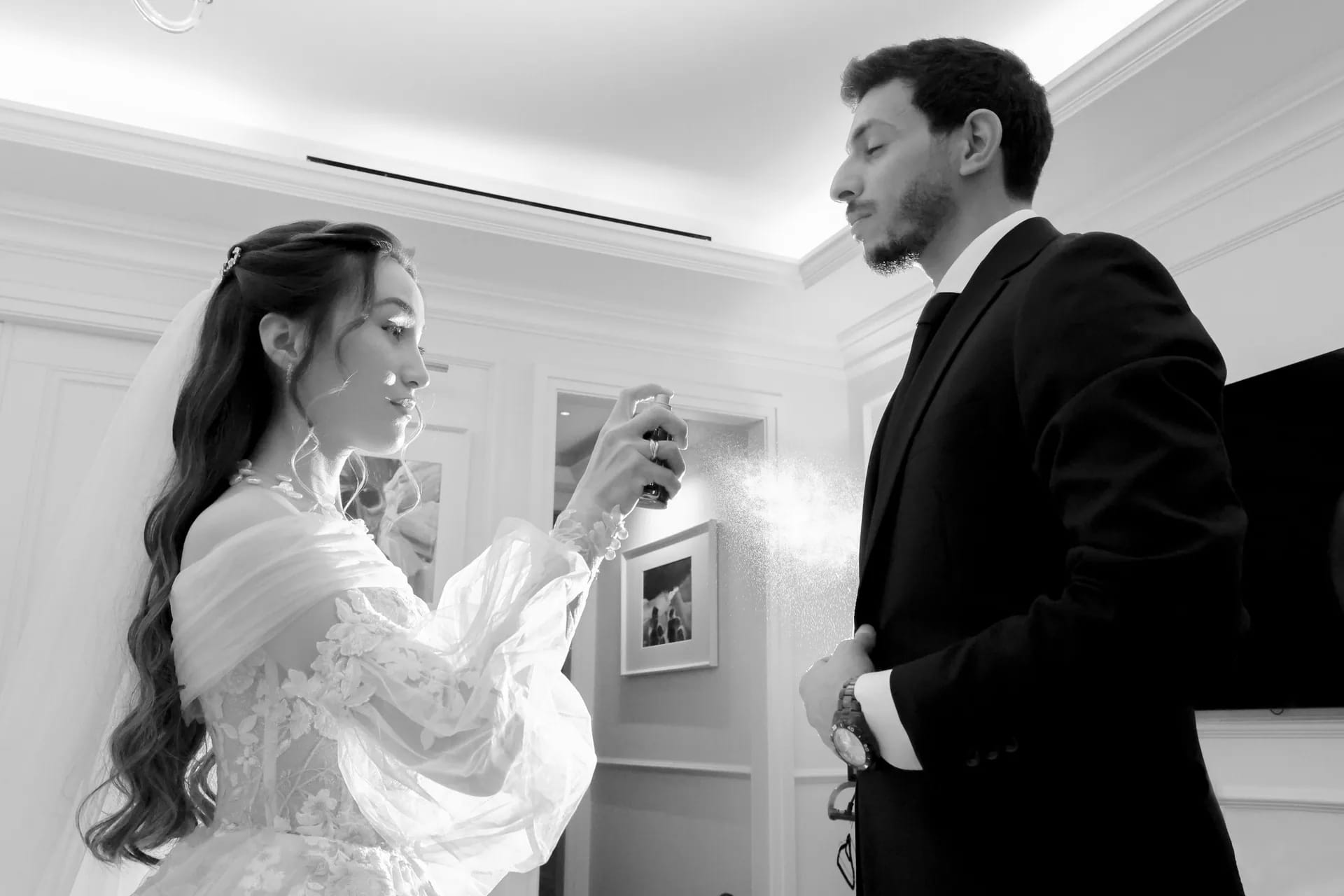 A groom kissing his bride's cheek under a crystal chandelier