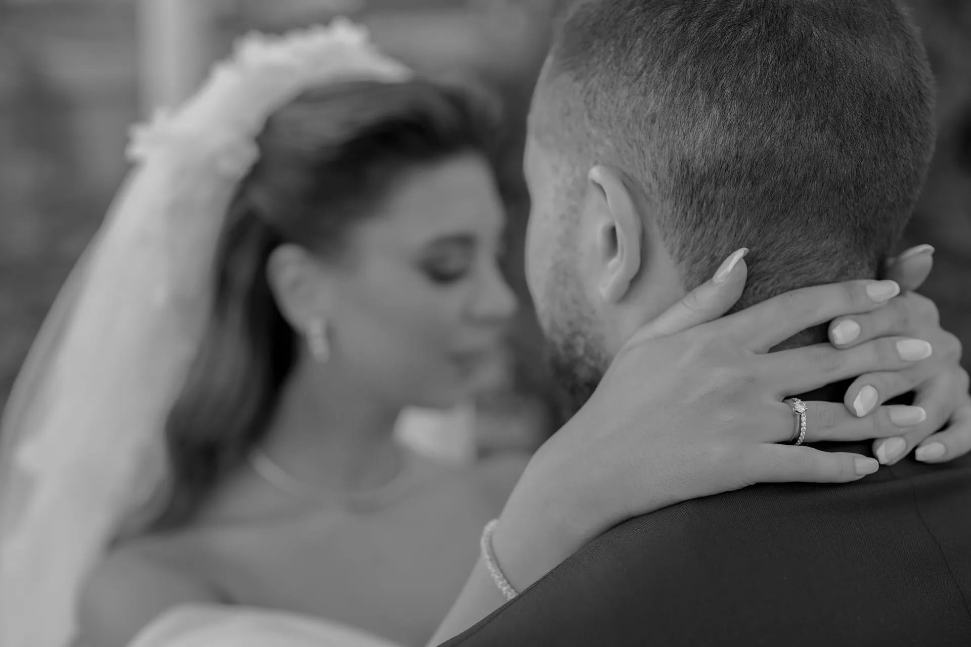 A groom holding his bride close, in black and white