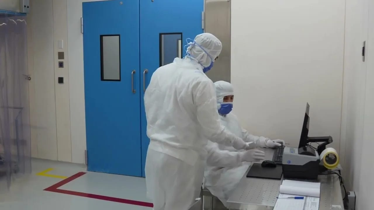 Technicians in cleanroom suits at a pharmaceutical production line