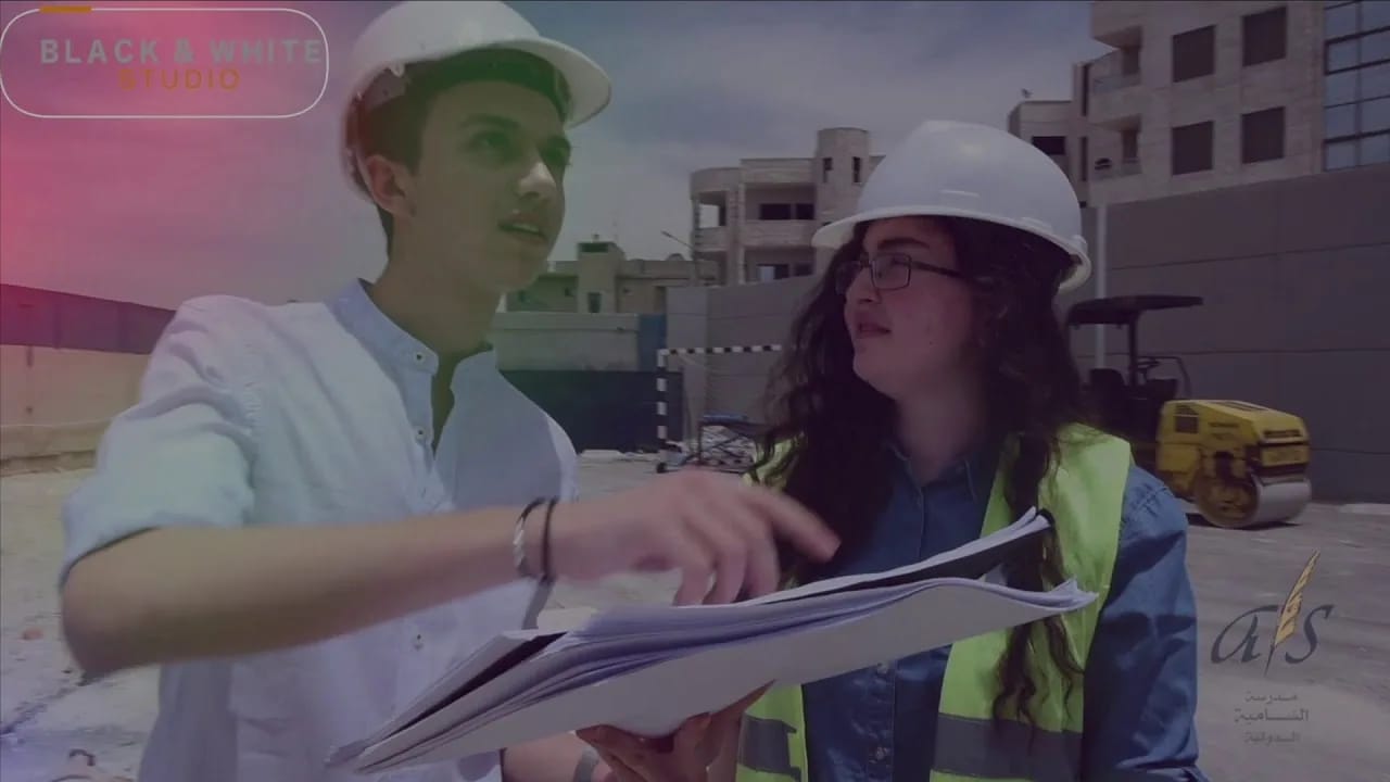 Students in hard hats reviewing plans on a school building site