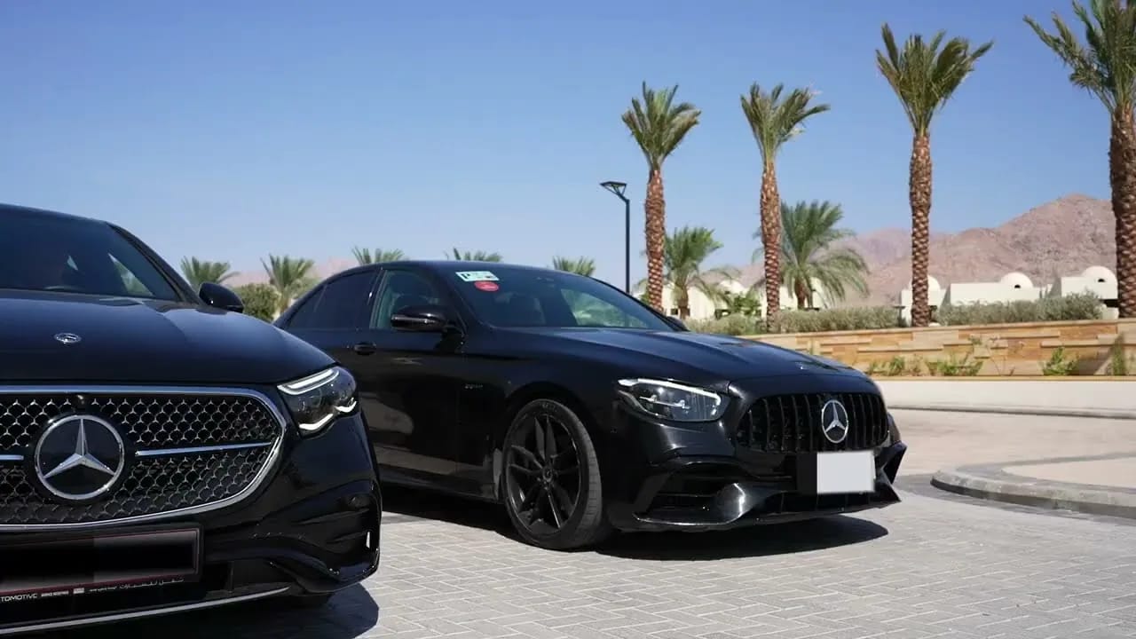 Two black Mercedes cars parked under palm trees