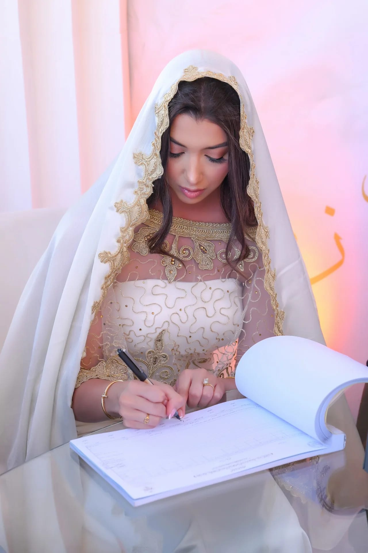 A bride signing the marriage contract at her katb kitab