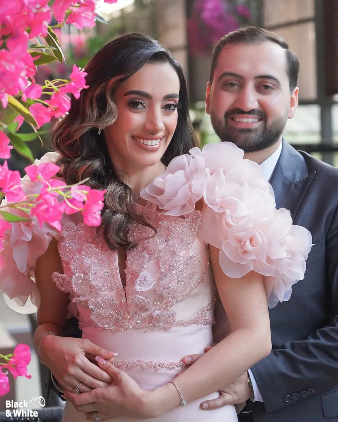 A bride in a pink gown and her groom among bougainvillea