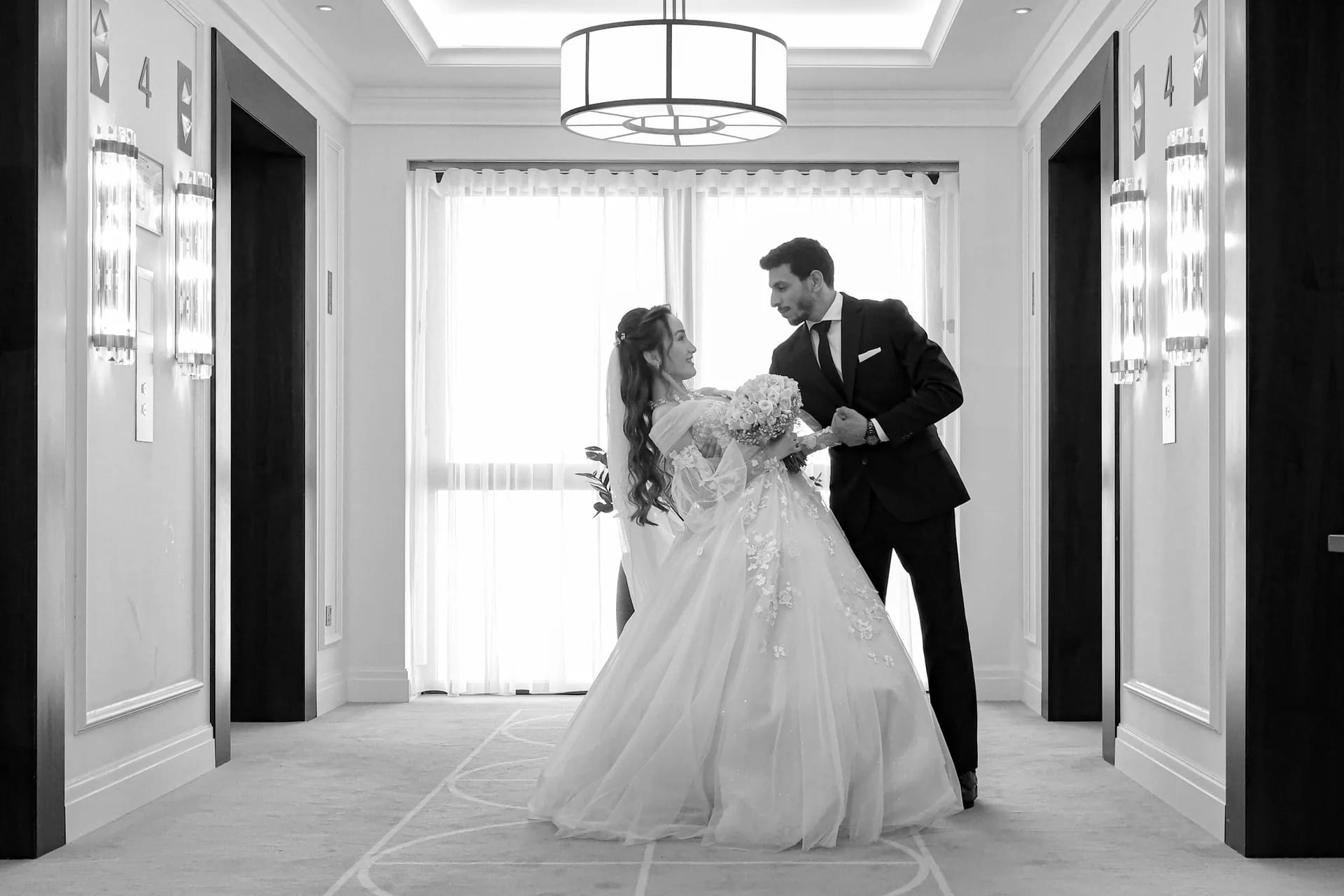 A couple in the middle of an elegant hallway, in black and white