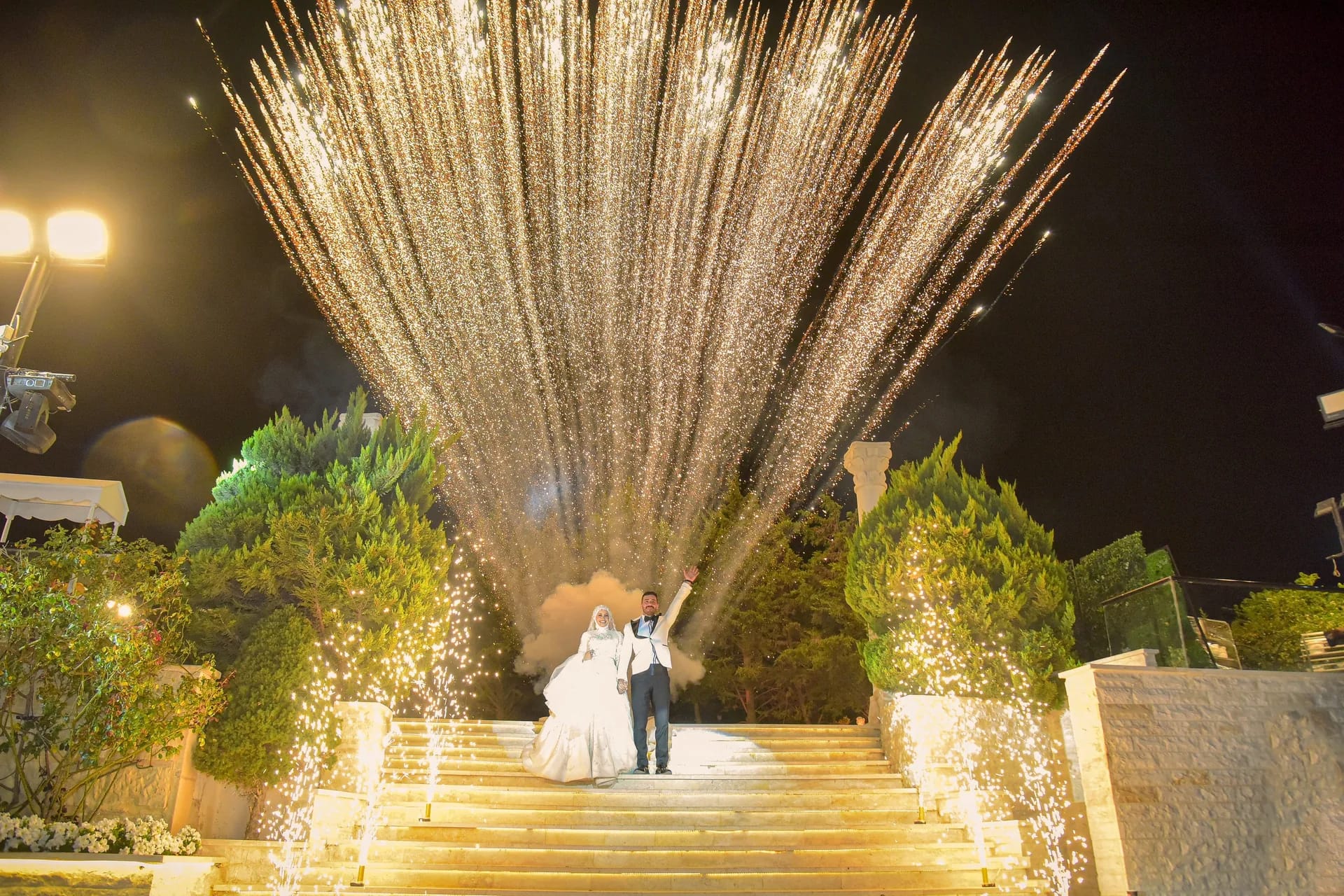 Sparklers bursting over the couple on a lit staircase at night