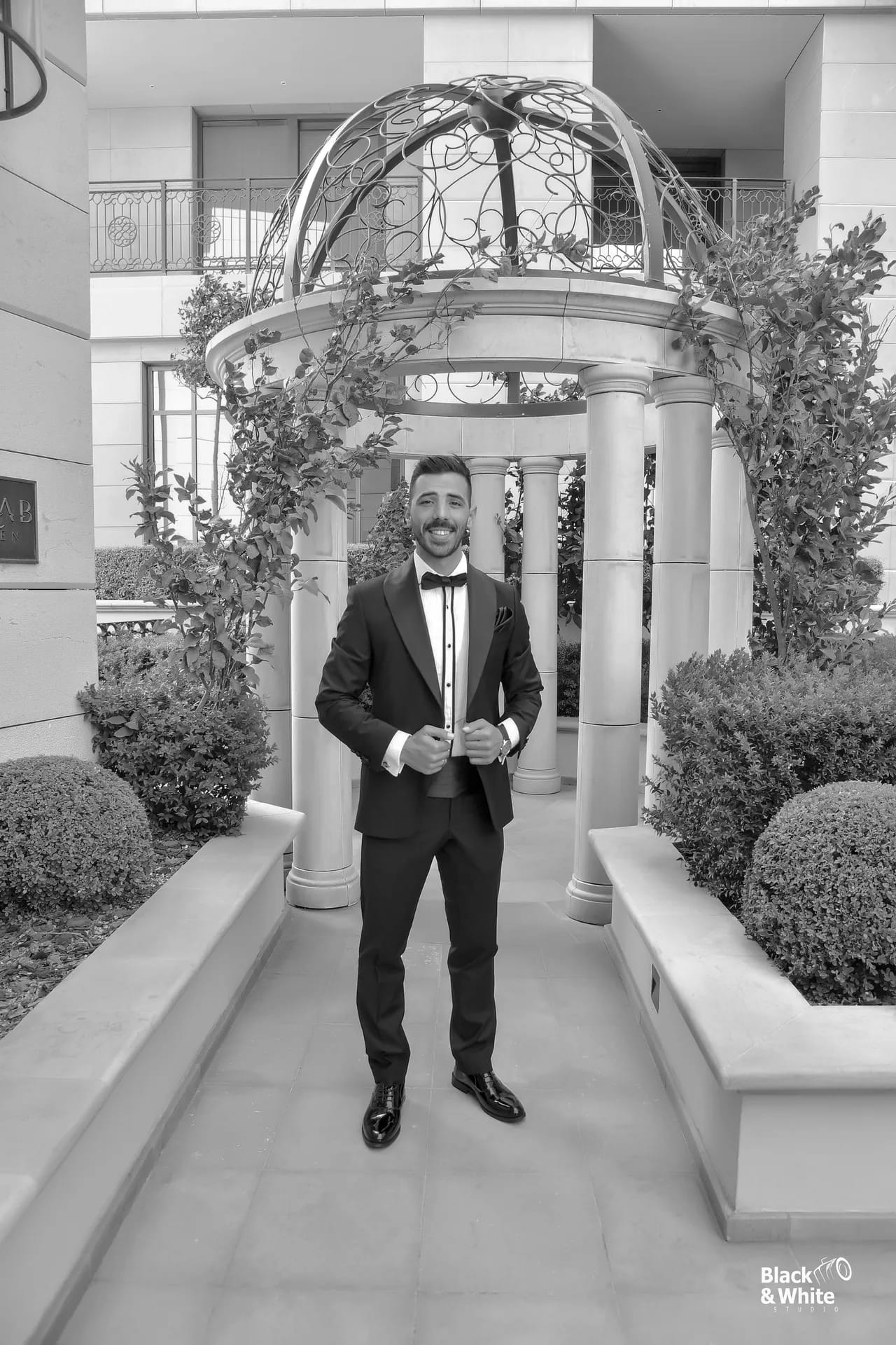 A groom in a black suit beneath a stone archway