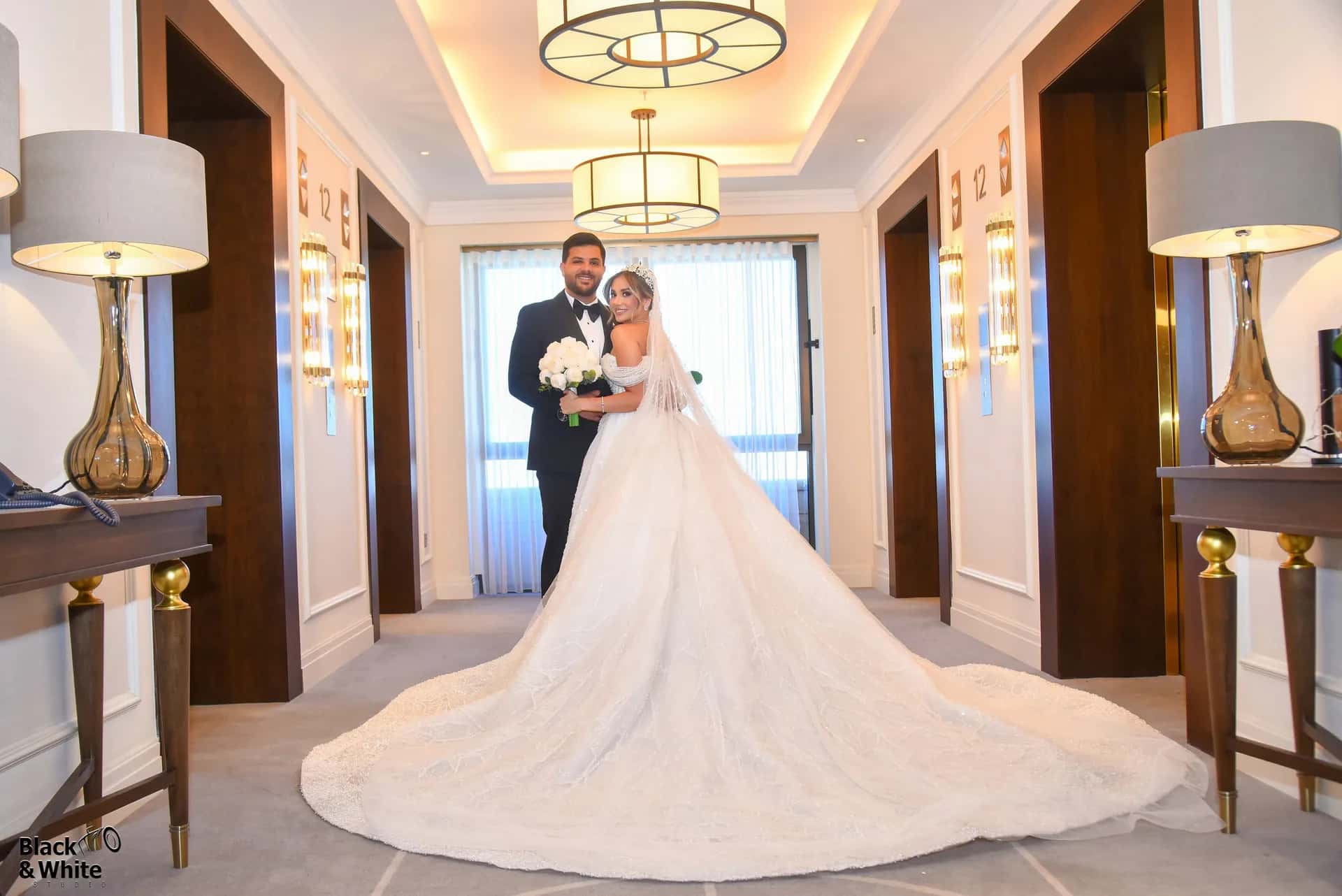 A couple at the end of a lamplit hotel corridor