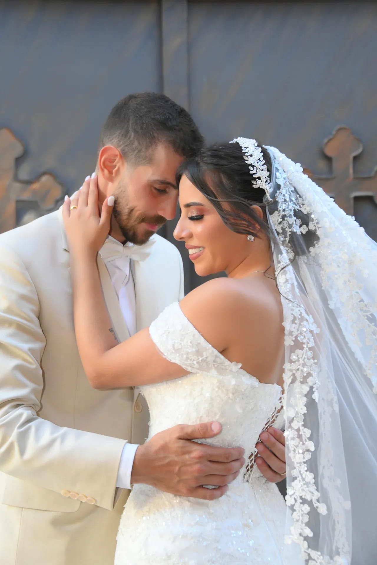 A groom in a cream suit embracing his bride