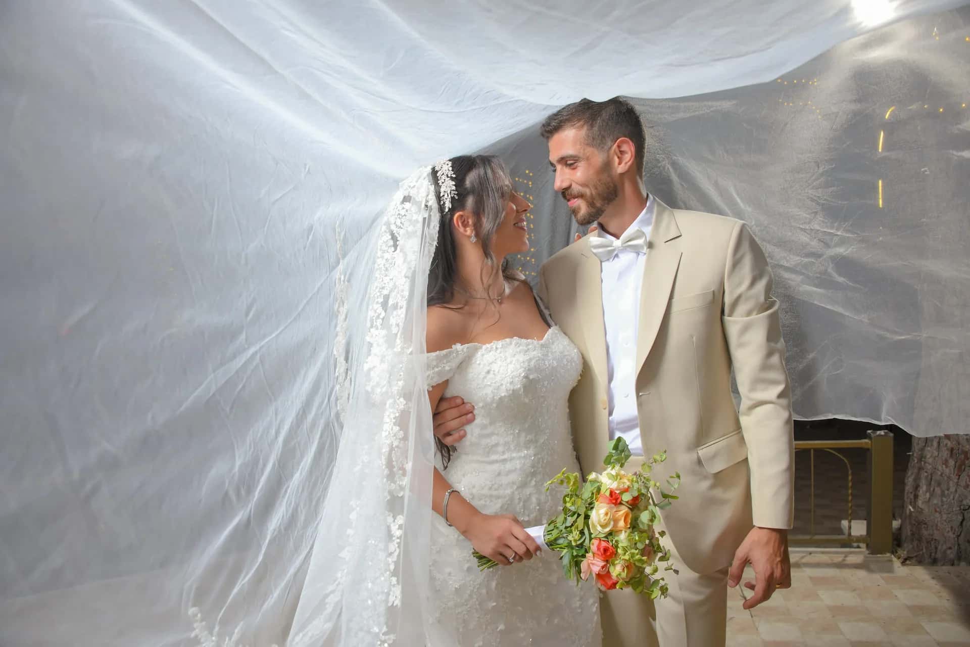 A couple beneath a veil held open like a canopy