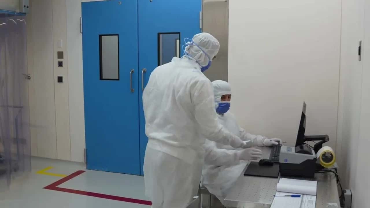Technicians in cleanroom suits at a pharmaceutical production line
