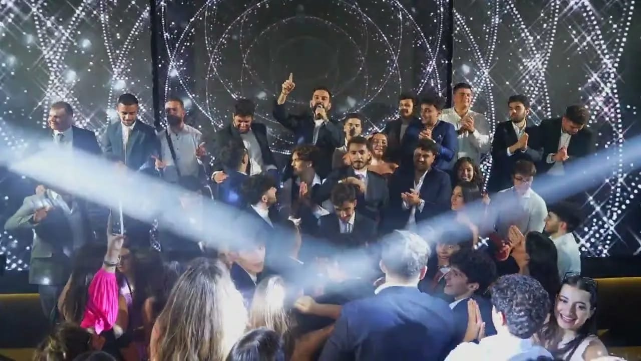 Graduates dancing under stage light at a school prom night